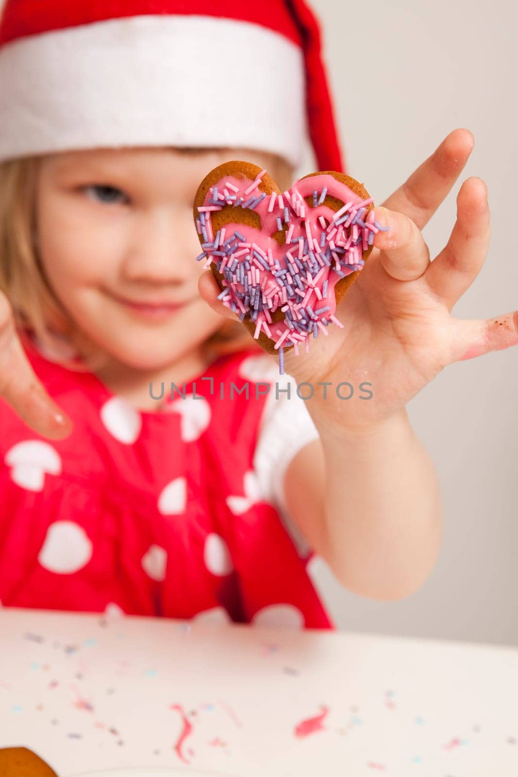 Girl holding a heart shaped decorated Christmas gingerbread