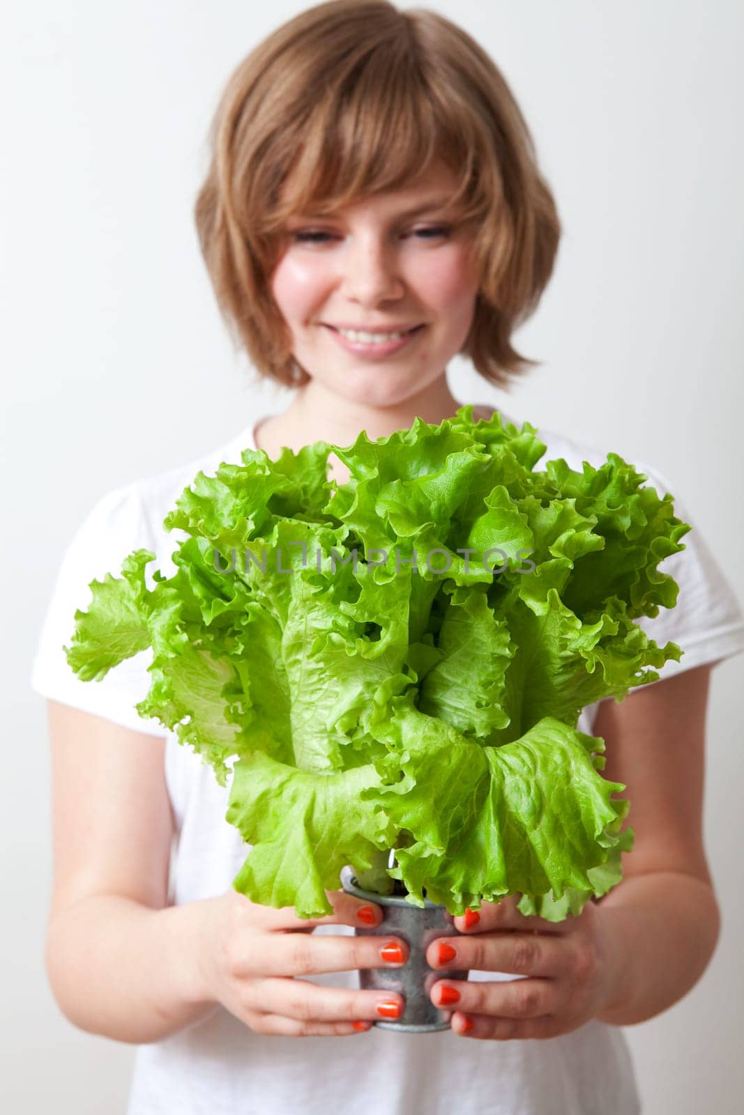 Young caucasian woman holding fresh green lettuce