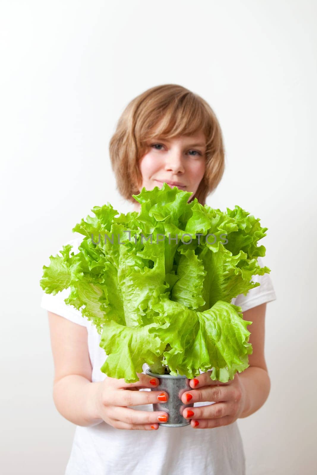 Young caucasian woman holding fresh green lettuce