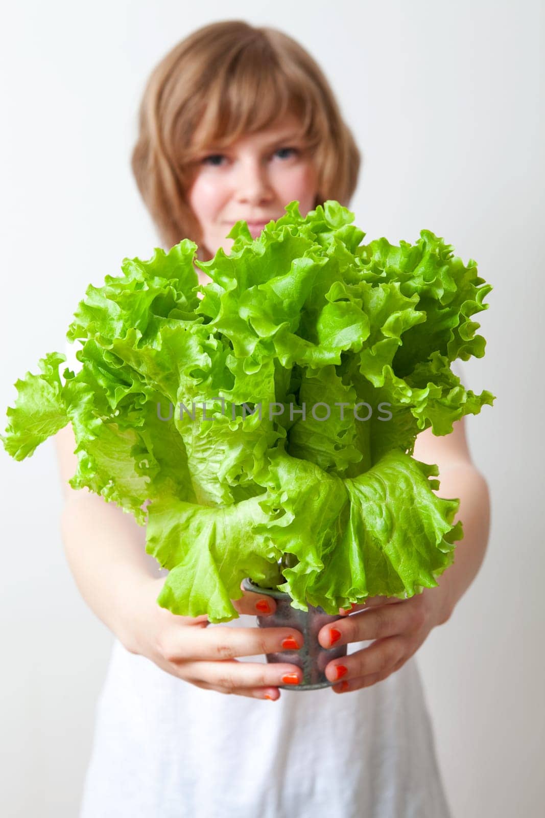 Young caucasian woman holding fresh green lettuce