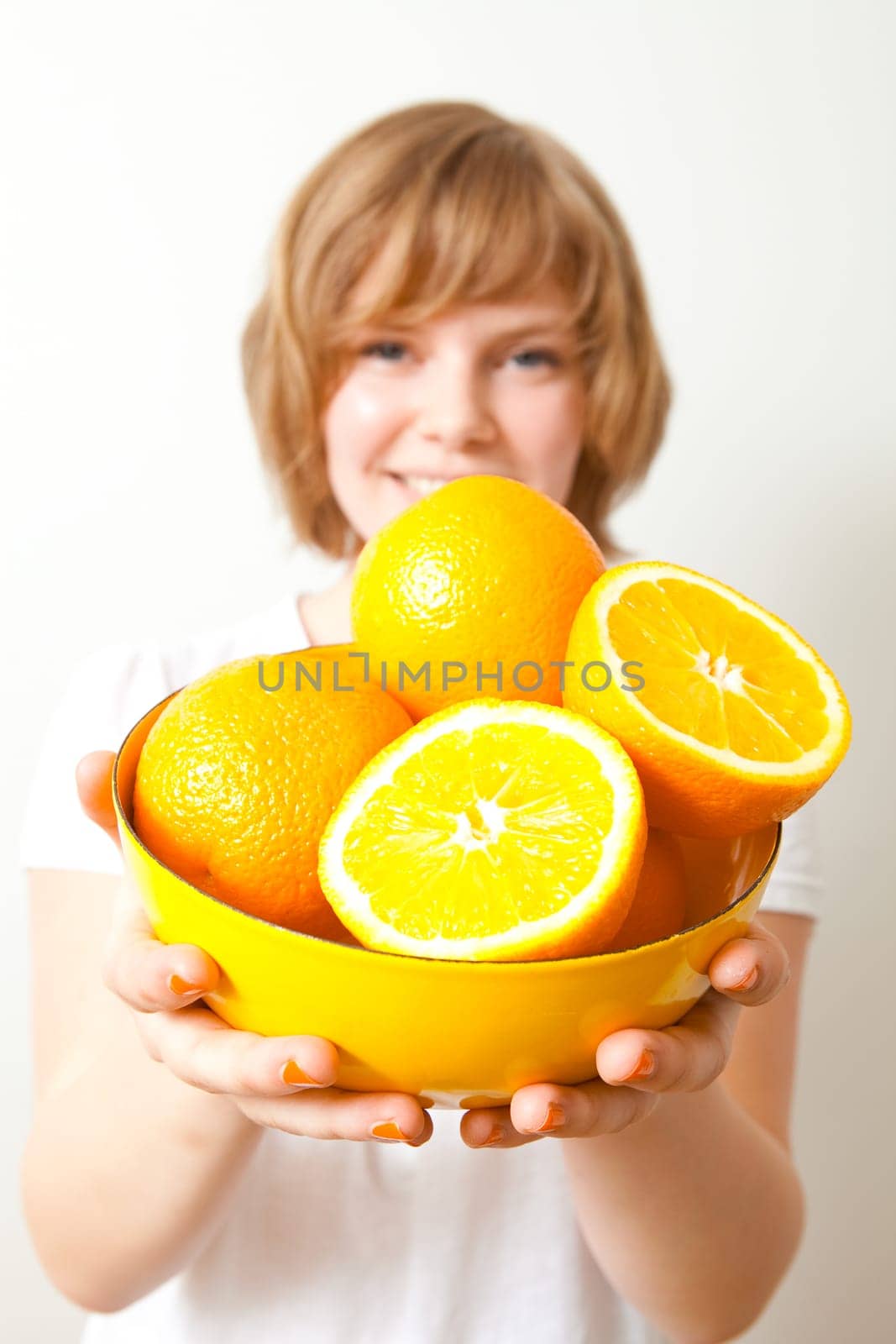 Young woman holding a bowl of fresh oranges. Studio shot.