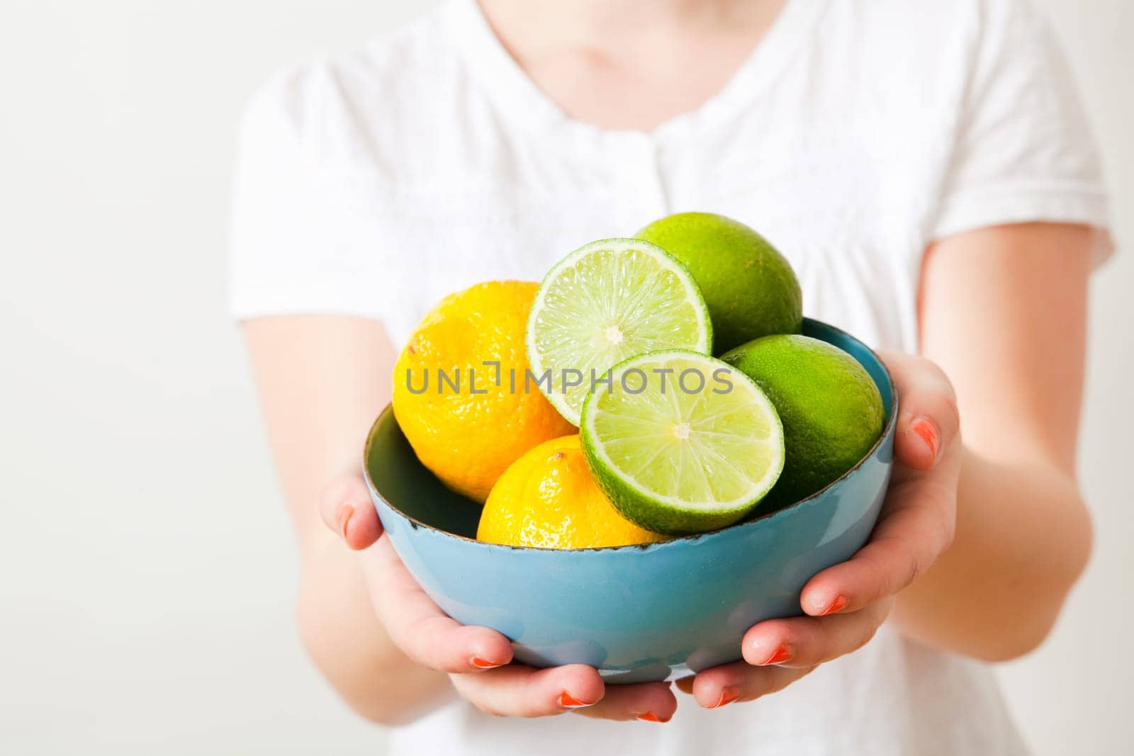 Young woman holding a bowl of fresh lemon and lime