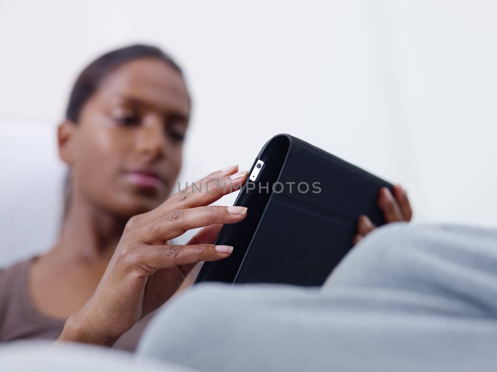 close up of mid adult indian woman relaxing on sofa and using touch pad computer. selective focus, copy space