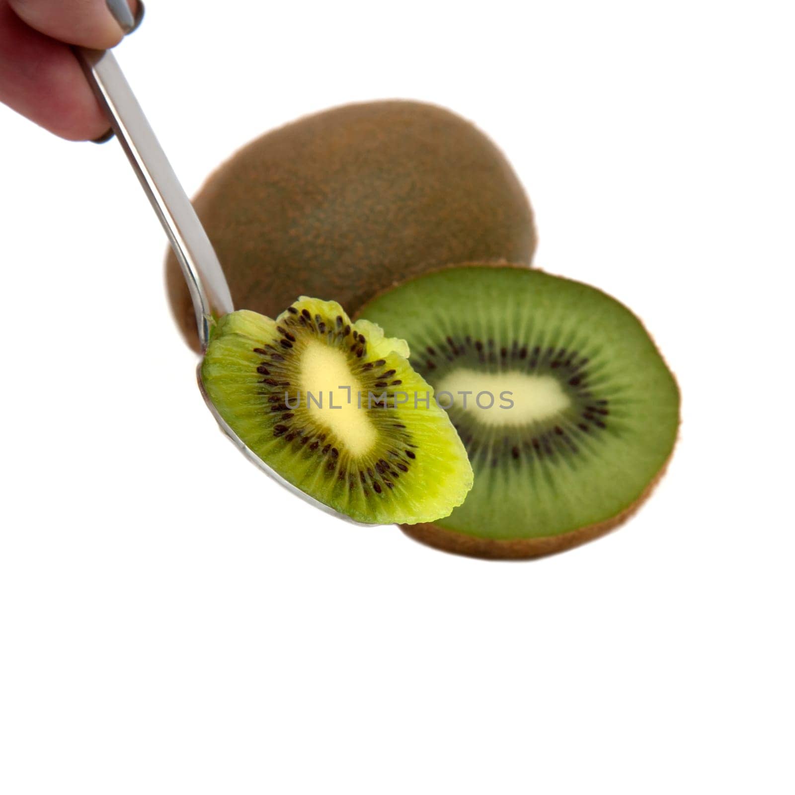 Kiwi on spoon with a whole and a half kiwi in the background
