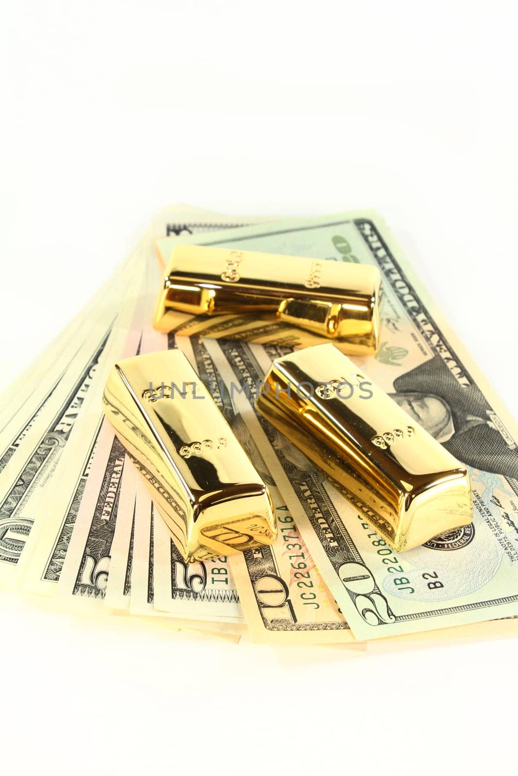 Dollar bills and gold bars against white background