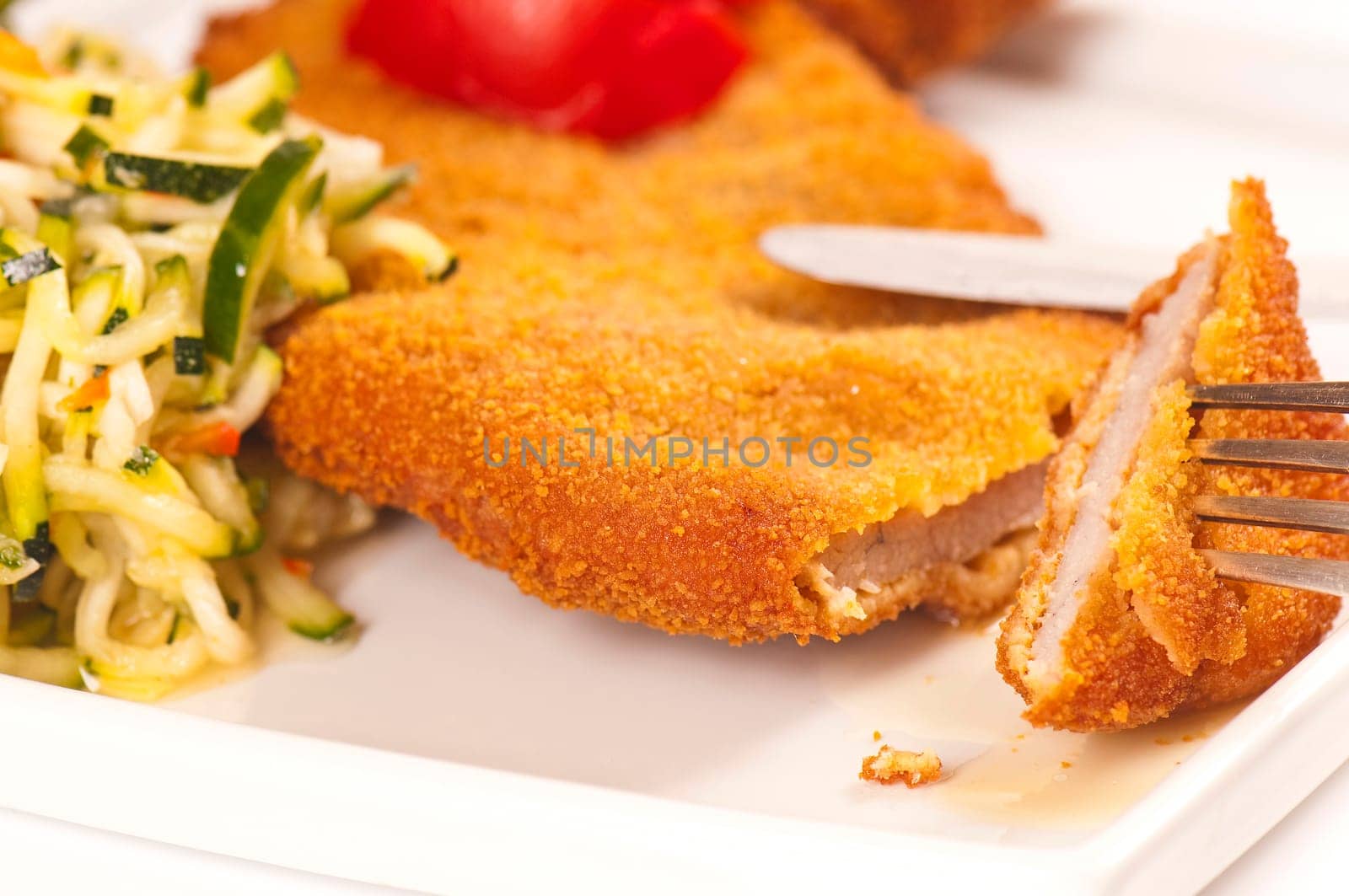 Schnitzel with tomato slices and zucchini salad