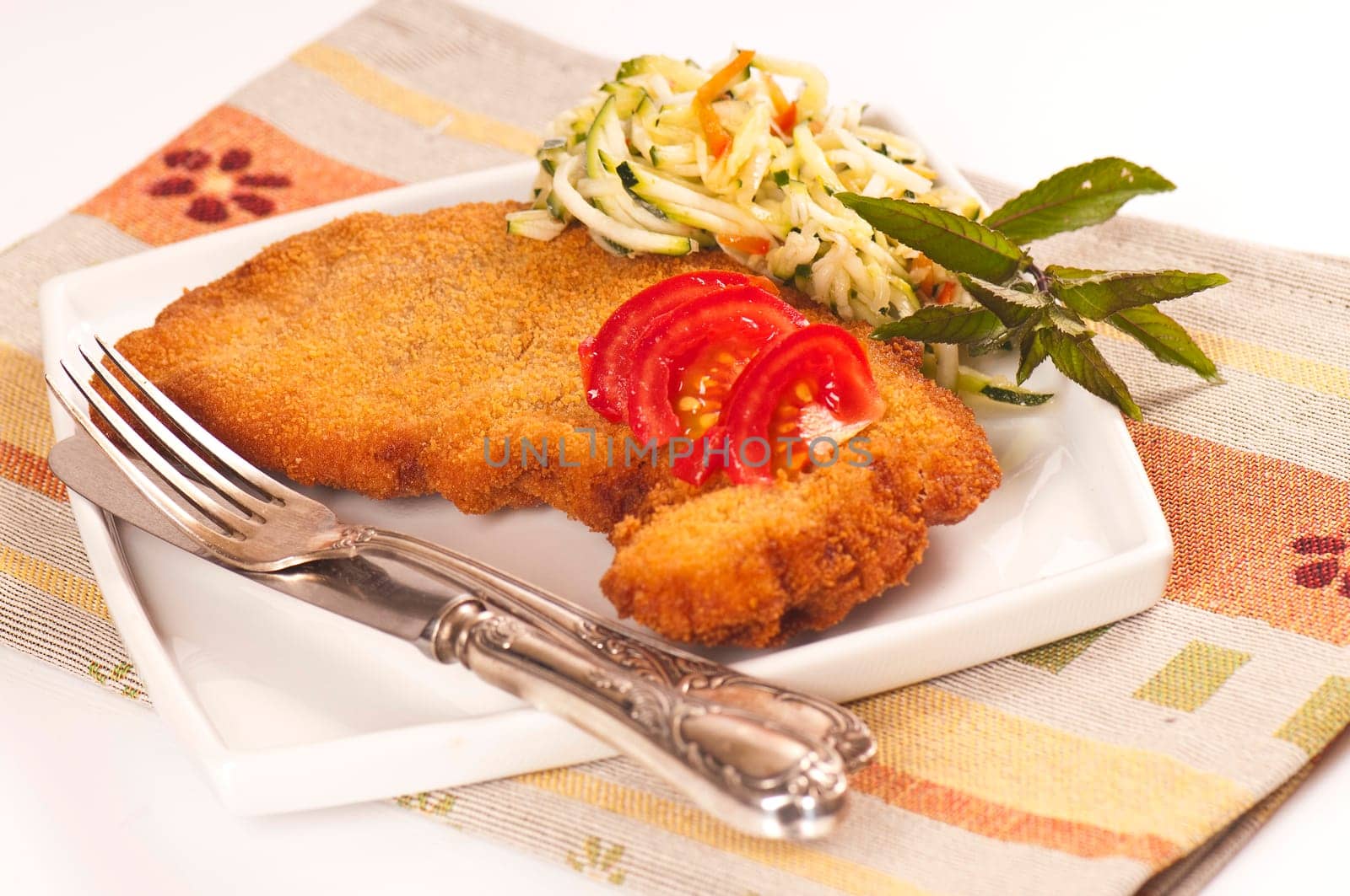 Schnitzel with tomato slices and zucchini salad