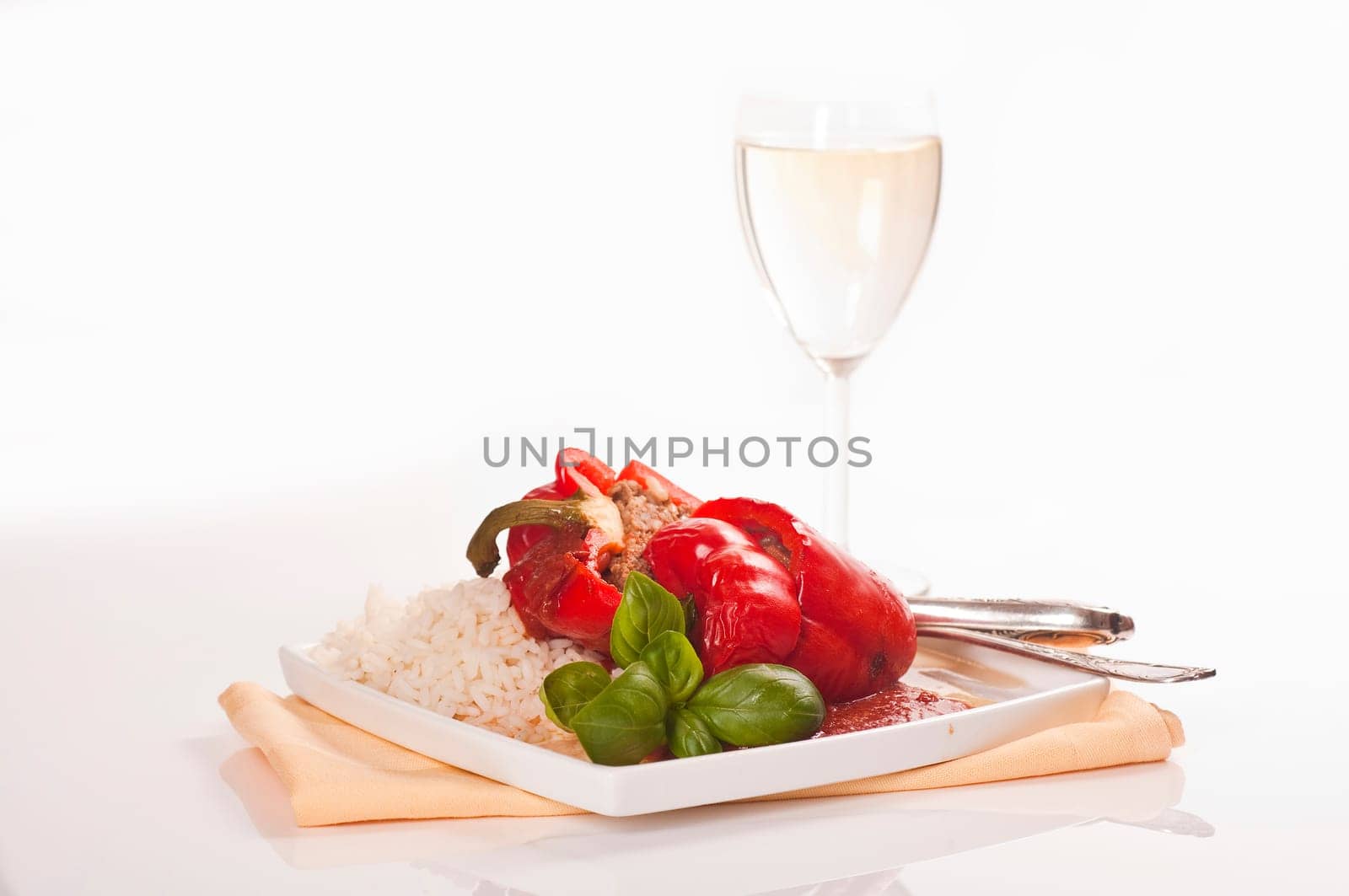 stuffed red peppers with rice and herbs served on plates with wine glass