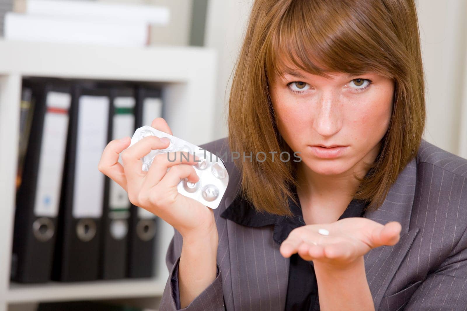 stressed businesswoman holding pills in her hand in office