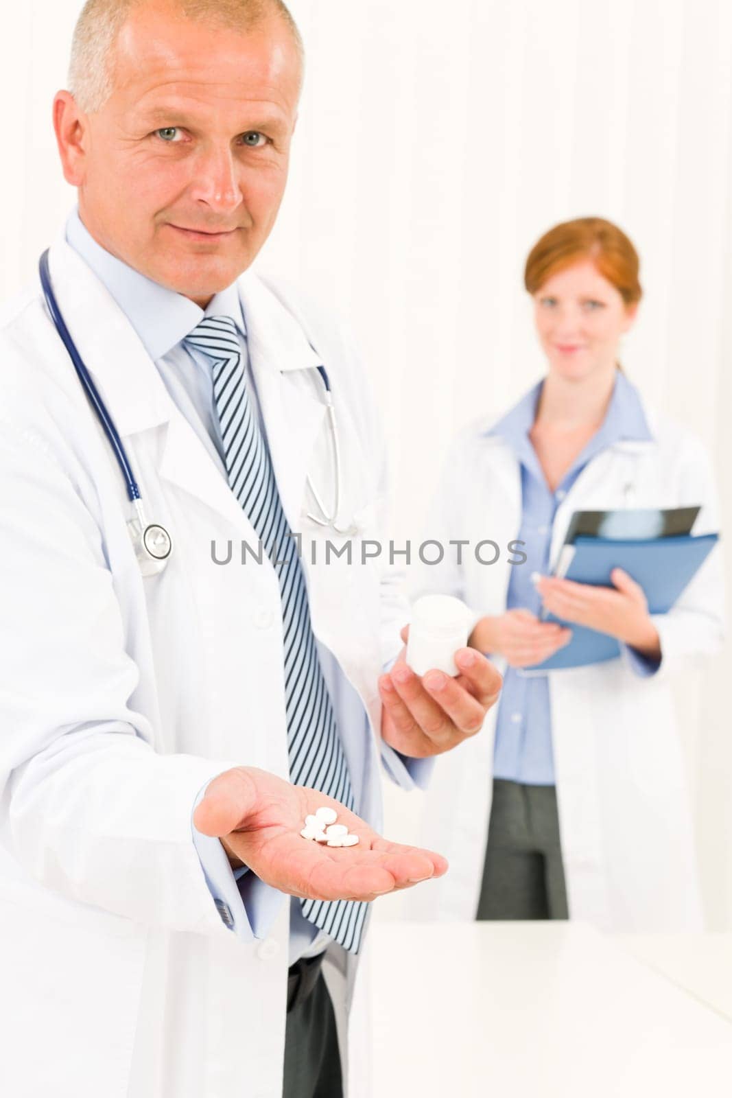 Medical doctor team senior male holding pills young female colleague