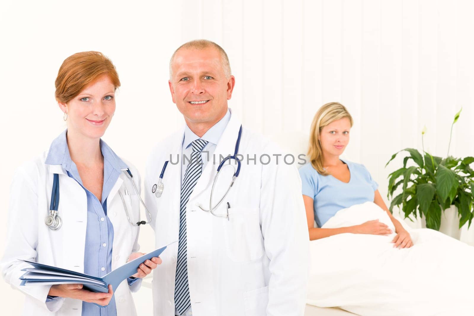 Two medical doctors professional with hospital patient lying in bed