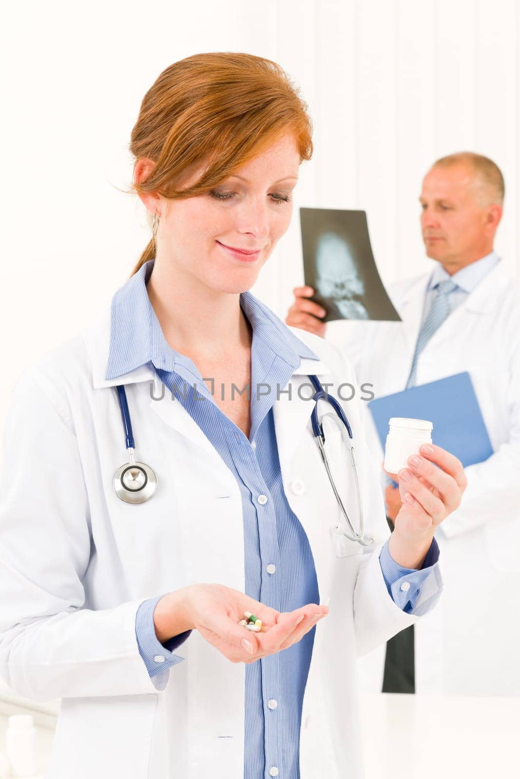 Medical doctor team young woman holding pills male senior colleague