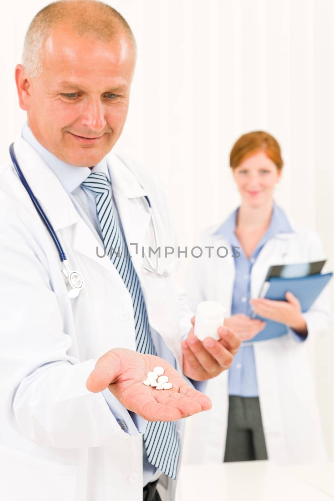 Medical doctor team senior male holding pills young female colleague
