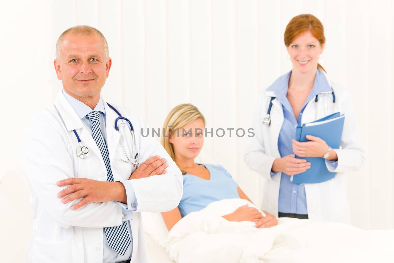 Two medical doctors professional with hospital patient lying in bed