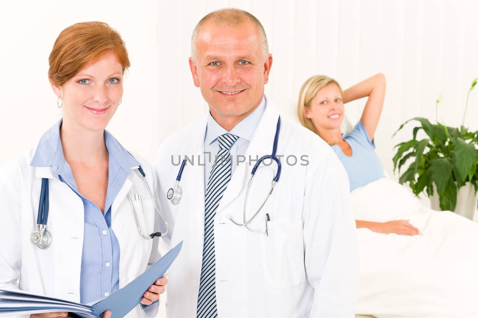 Two medical doctors professional with hospital patient lying in bed