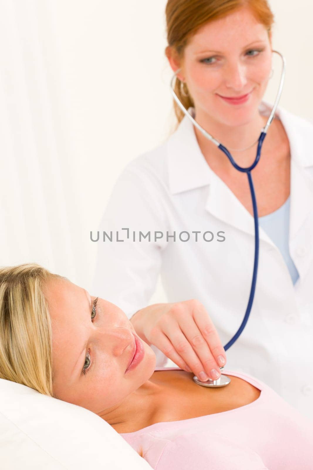 Medical professional doctor stethoscope examine woman patient lying in bed