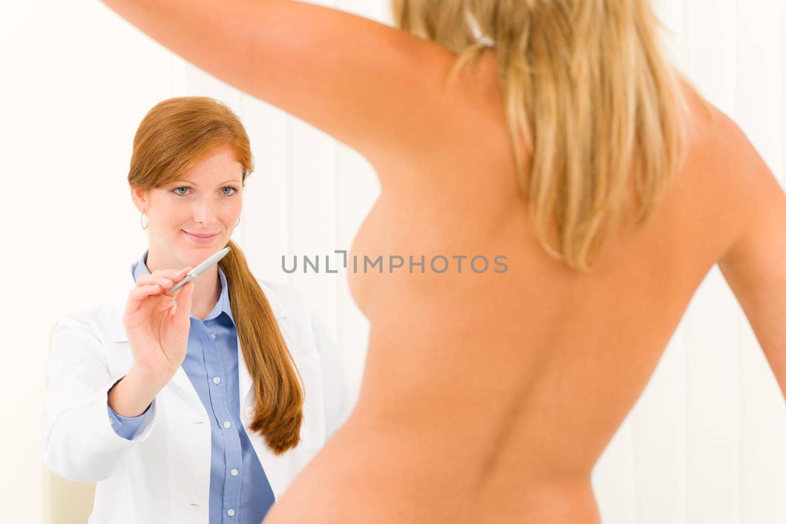 Plastic surgery female doctor examine blond woman patient breast shape