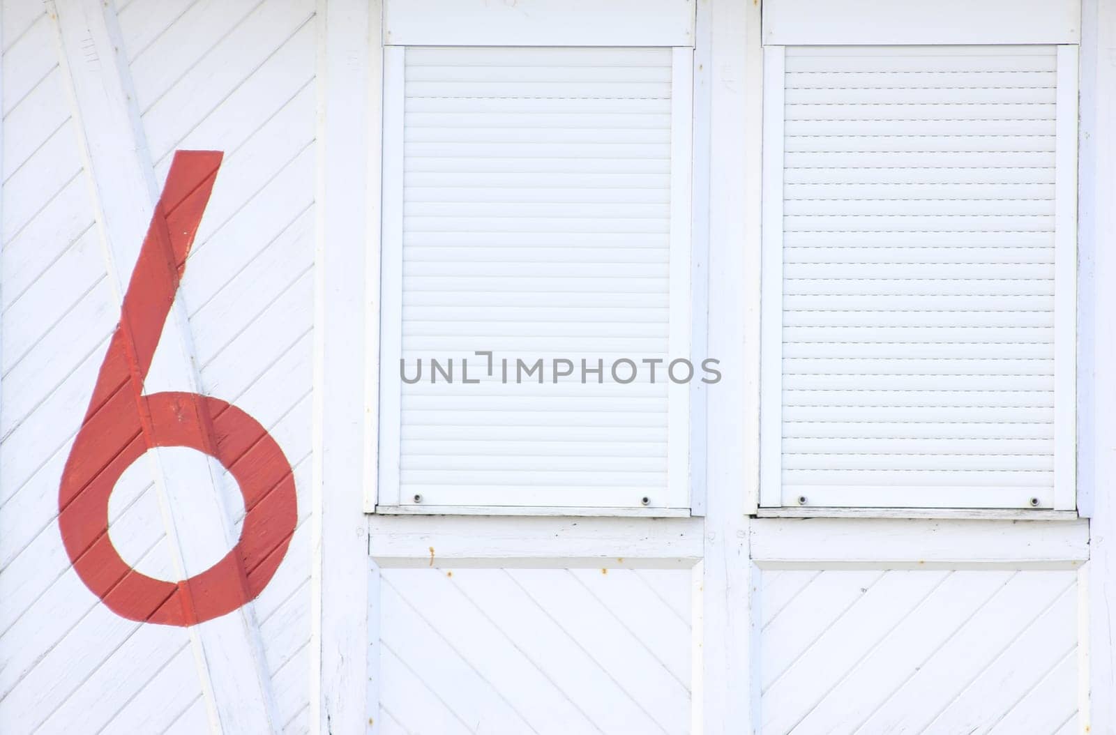 white wooden wall with two closed windows and the inscription with the number six