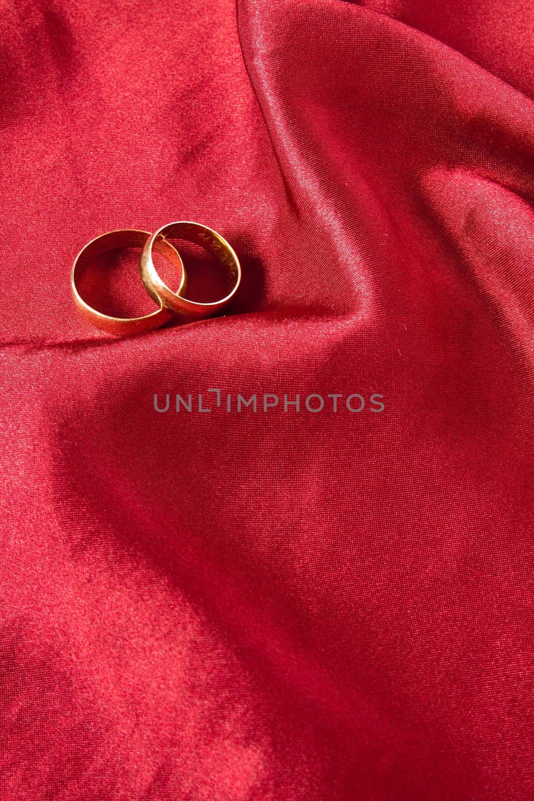 Two wedding rings on red satin background