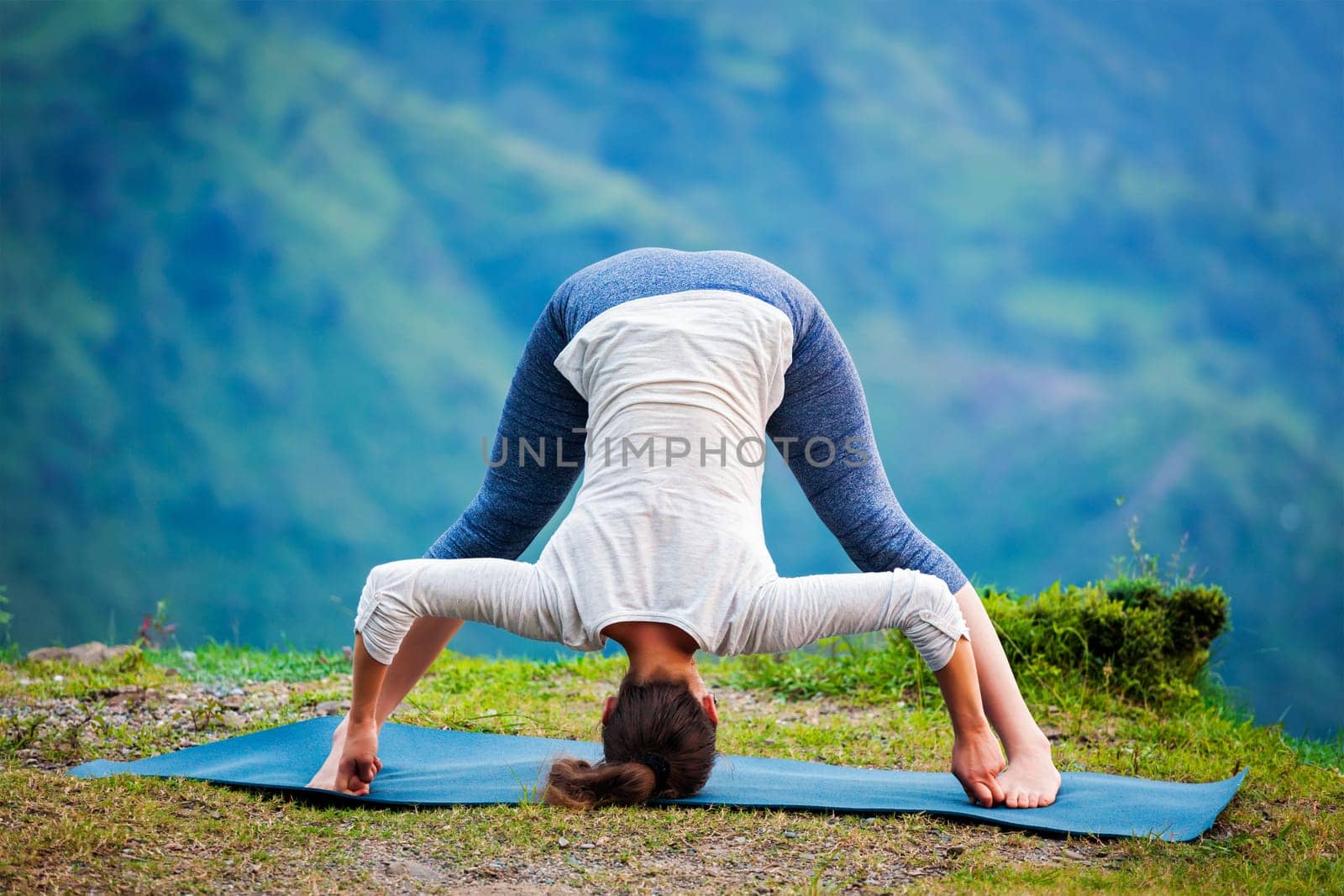 Woman doing Ashtanga Vinyasa Yoga asana Prasarita padottanasana by dimol
