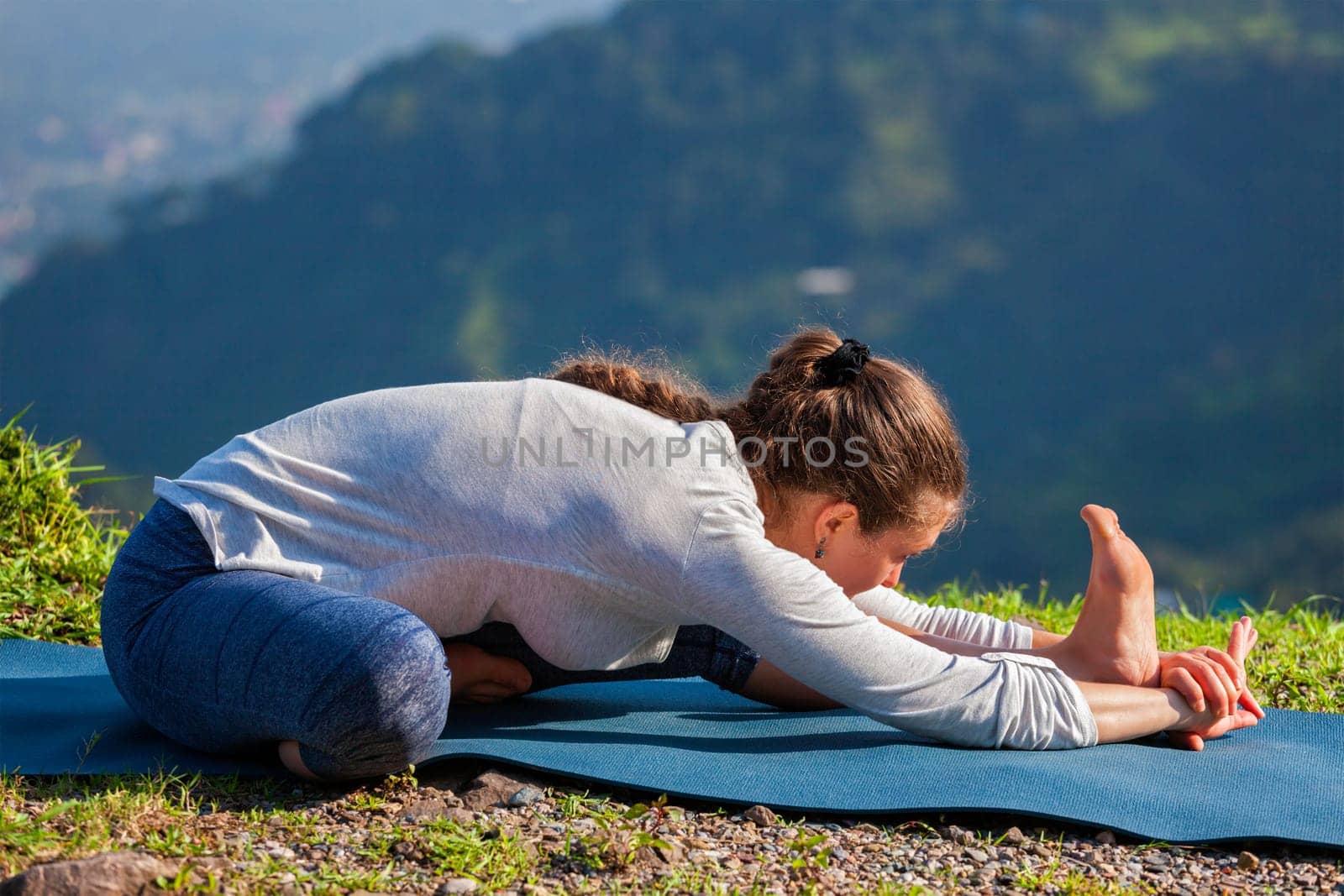 Yoga outdoors - woman doing Ashtanga Vinyasa yoga Janu Sirsasana A head to knee stretching asana position outdoors