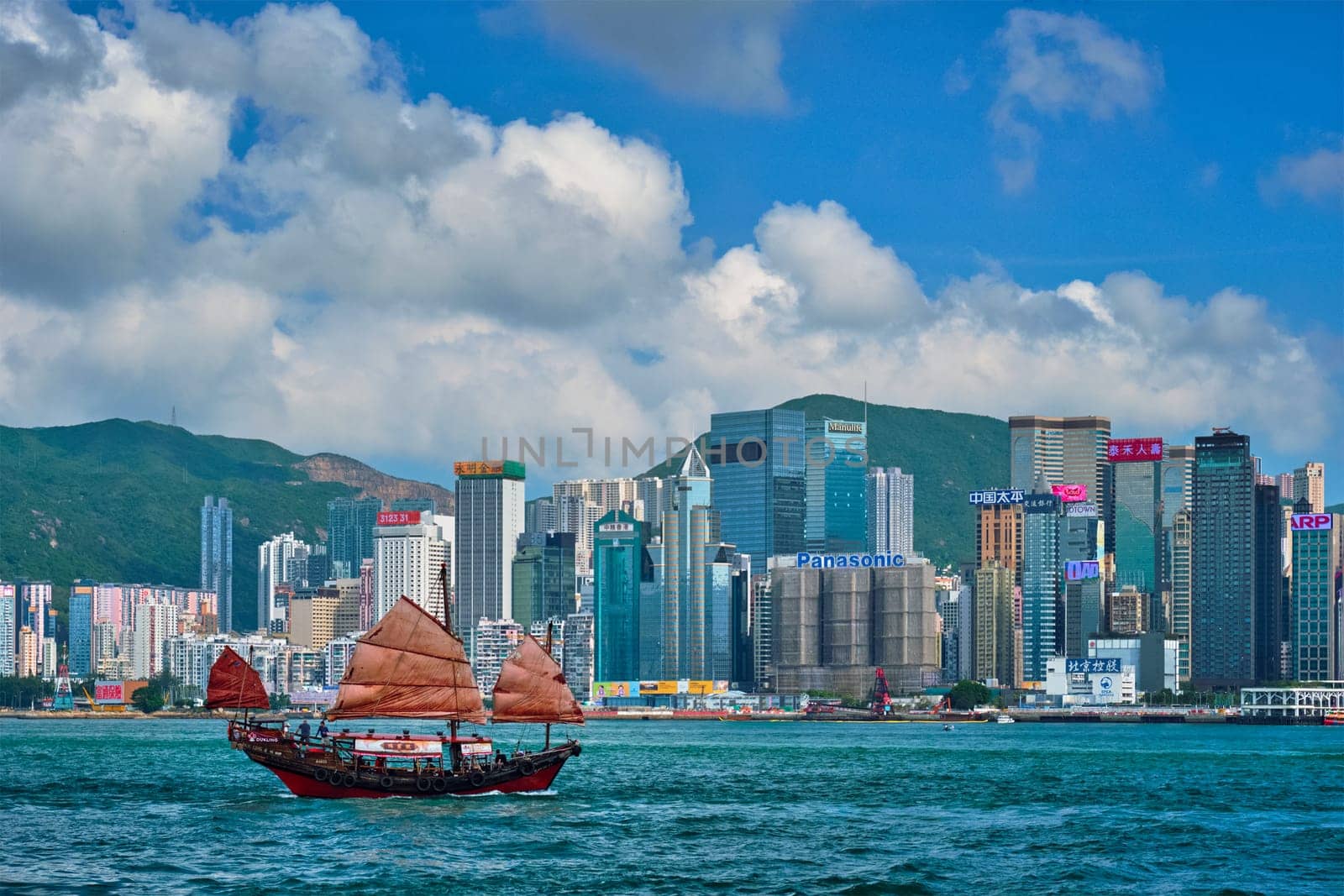 HONG KONG, CHINA - MAY 1, 2018: Hong Kong skyline cityscape downtown skyscrapers over Victoria Harbour in the evening with junk tourist ferry boat on sunset. Hong Kong, China