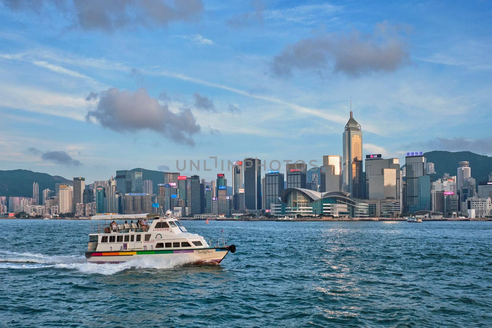 HONG KONG, CHINA - MAY 1, 2018: Hong Kong skyline cityscape downtown skyscrapers over Victoria Harbour in the evening with tourist boat on sunset. Hong Kong, China