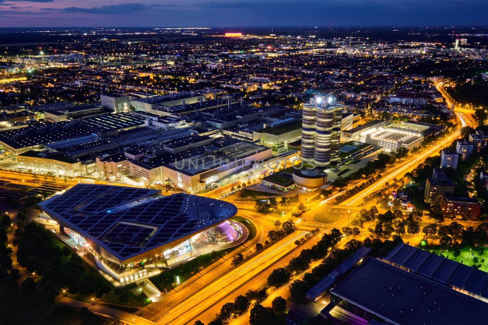 MUNICH, GERMANY - JULY 08, 2018: Aerial view of BMW Museum and BWM Welt and factory and Munich from Olympic Tower illuminated at night. BMW is a famous German luxury car automaker.