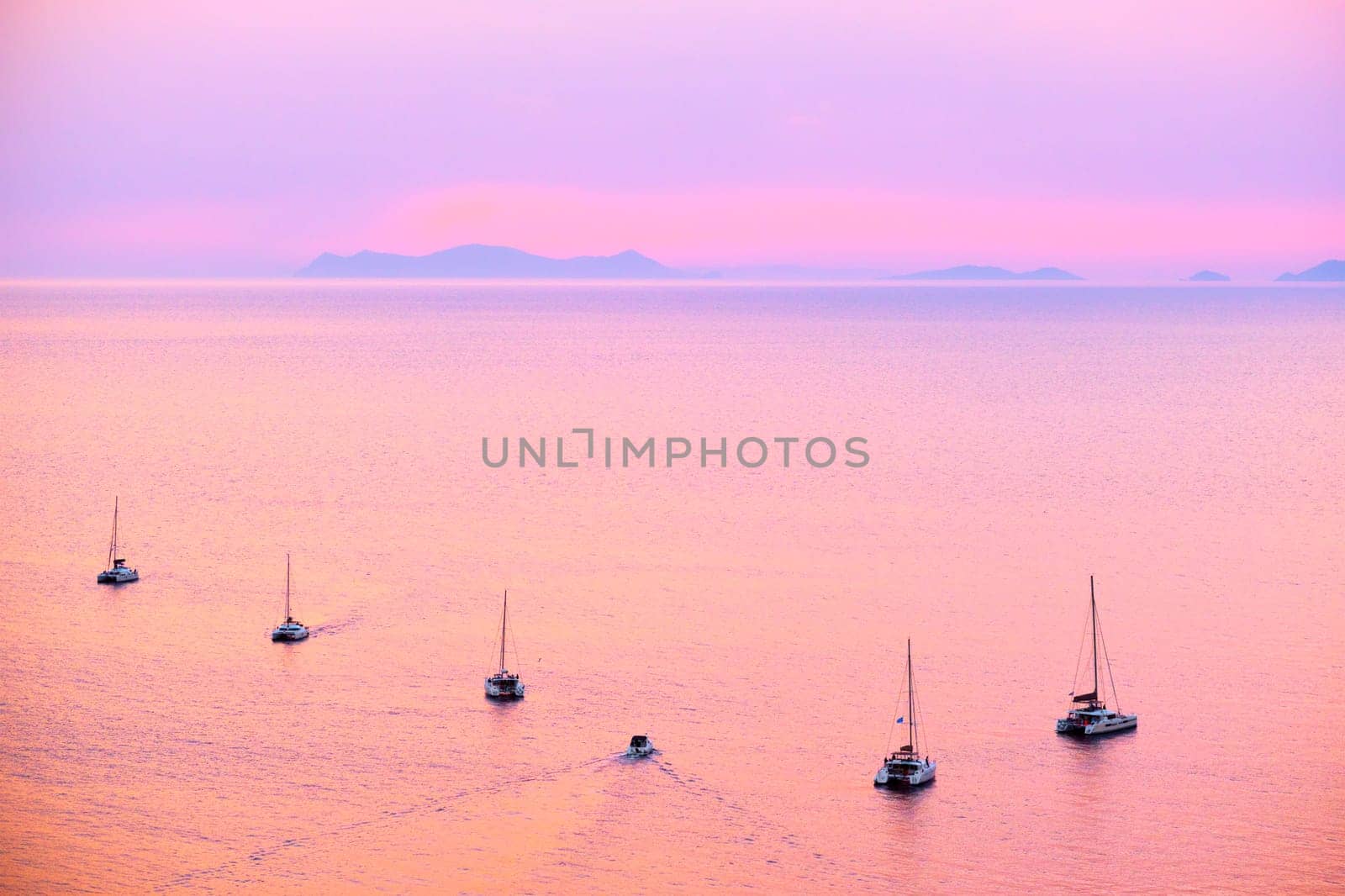Tourist yachts boat in Aegean sea near Santorini island with tourists watching sunset viewpoint. Santorini, Greece by dimol