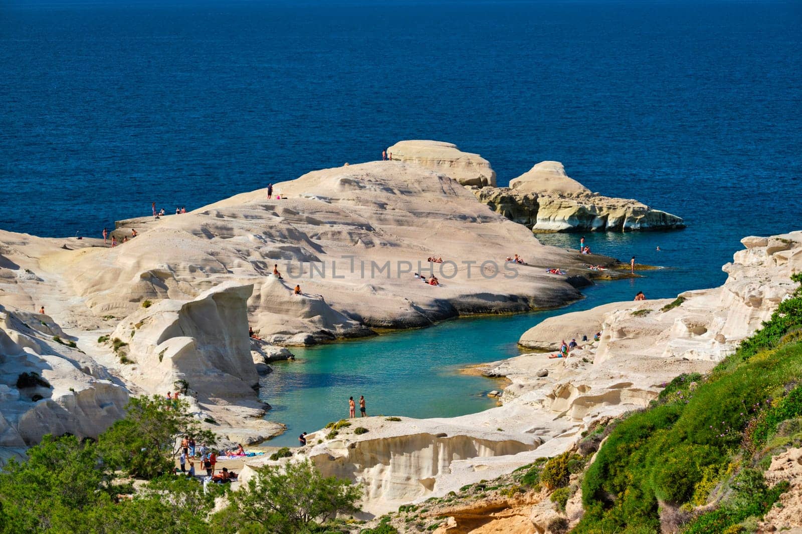 White rocks of famous tourist attraction of Milos island Sarakiniko beach with tourist relax and Aegean sea, Milos island , Greece