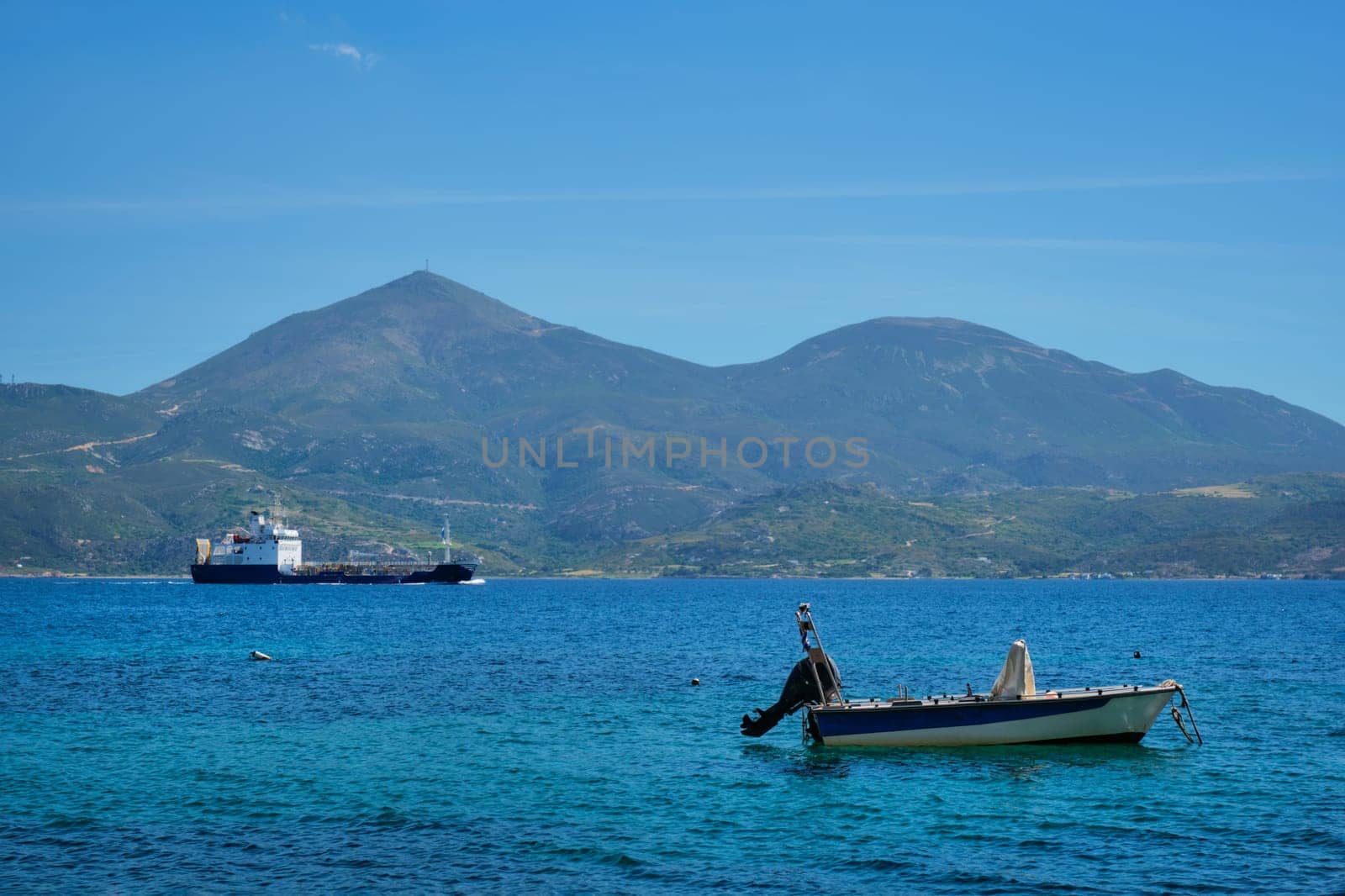 Greek fishing speed boat and cargo ship in the Aegean sea, Milos island, Greece