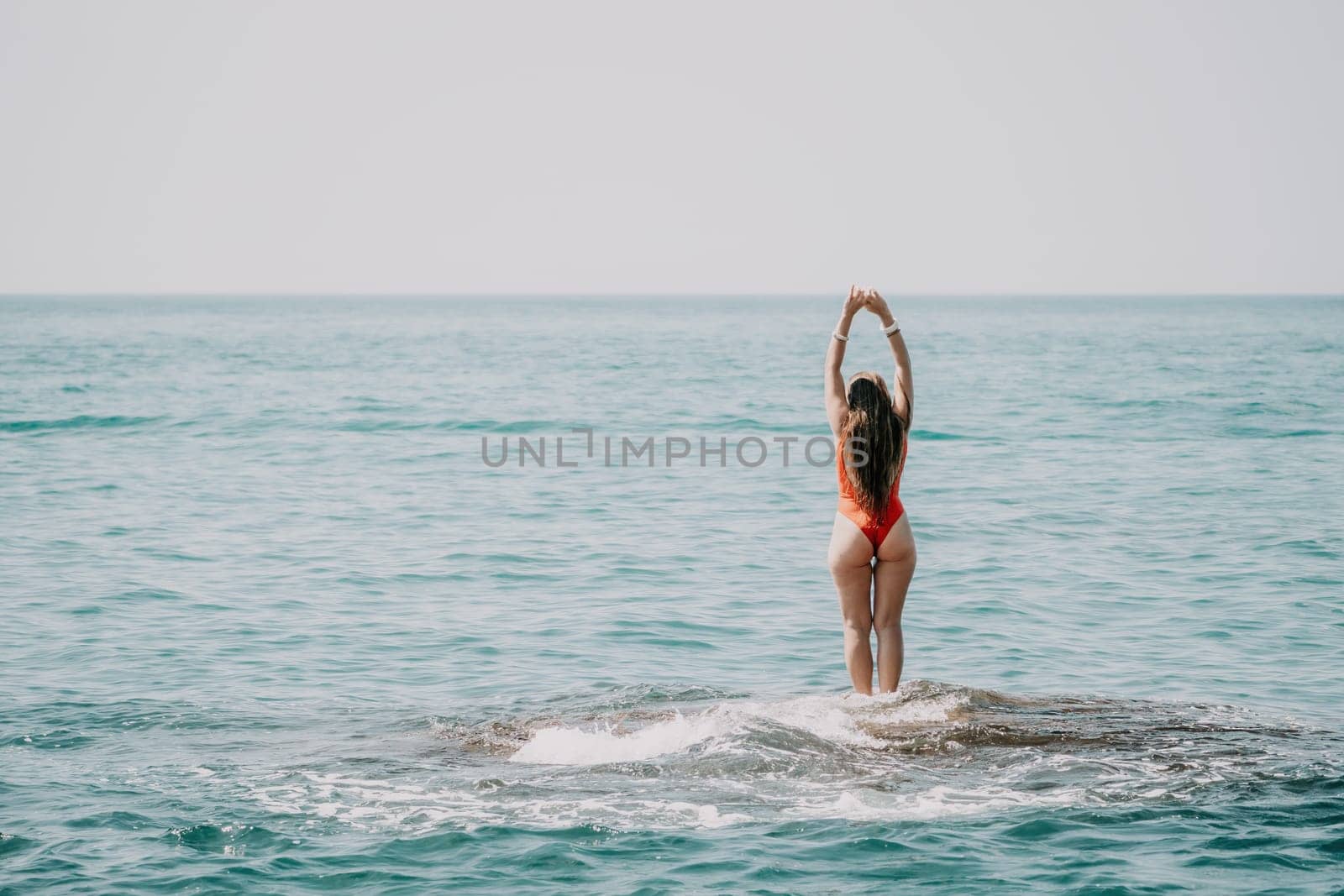 Woman sea yoga. Back view of free calm happy satisfied woman with long hair standing on top rock with yoga position against of sky by the sea. Healthy lifestyle outdoors in nature, fitness concept by panophotograph