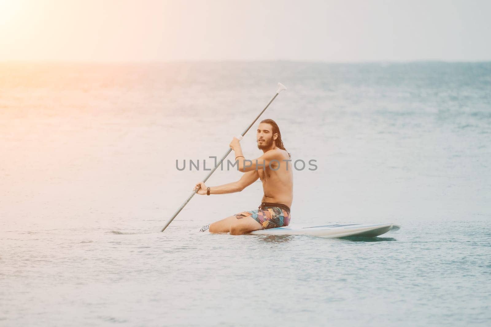 Sea woman and man on sup. Silhouette of happy young woman and man, surfing on SUP board, confident paddling through water surface. Idyllic sunset. Active lifestyle at sea or river. by panophotograph