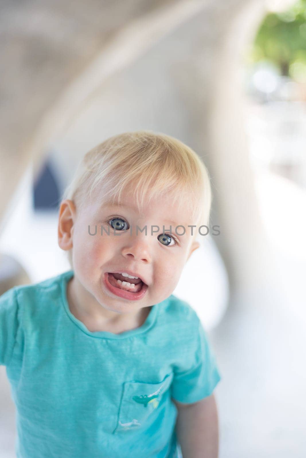 Portrait of cute little infant baby boy child playing on outdoor playground. Toddler plays on school or kindergarten yard