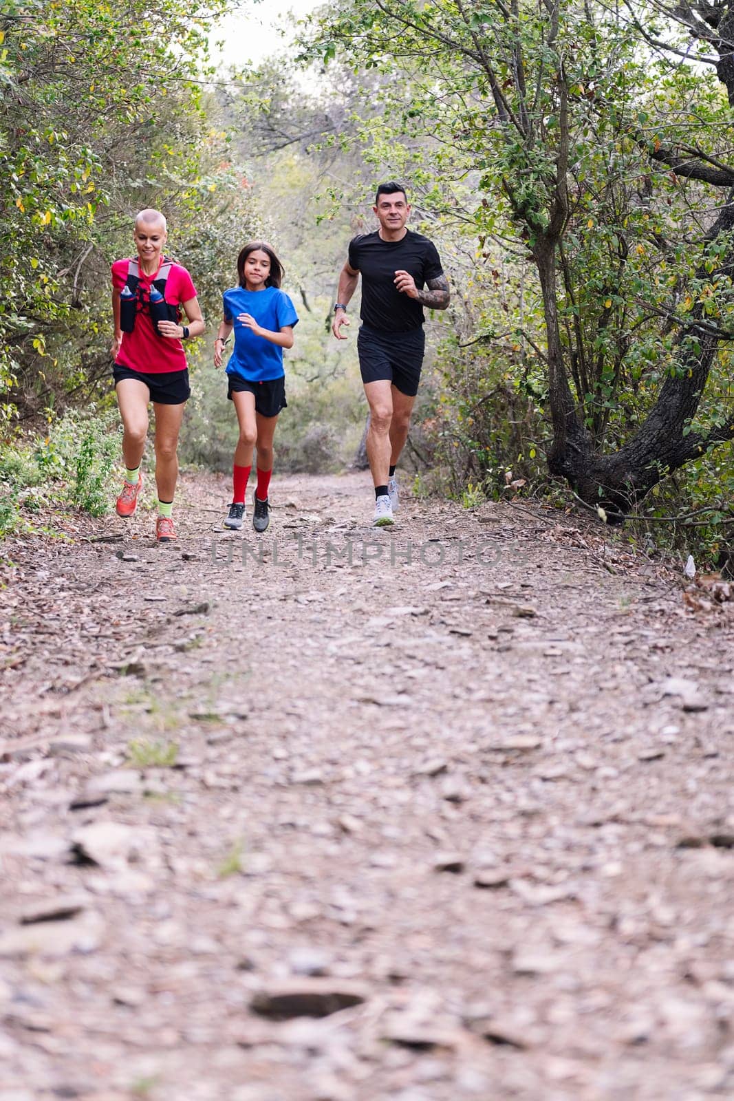 family practicing trail running in the forest, concept of sport in nature and healthy family lifestyle, copy space for text