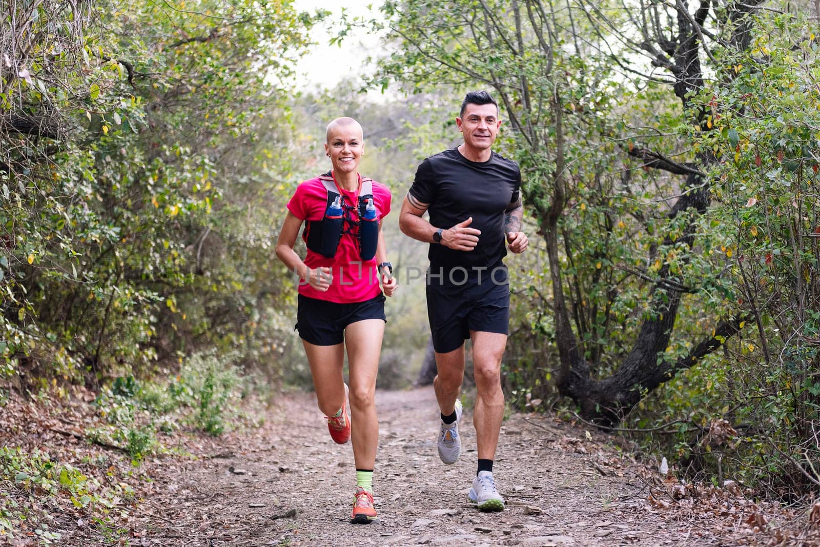 couple practicing trail running in the forest, concept of sport in nature and healthy lifestyle, copy space for text