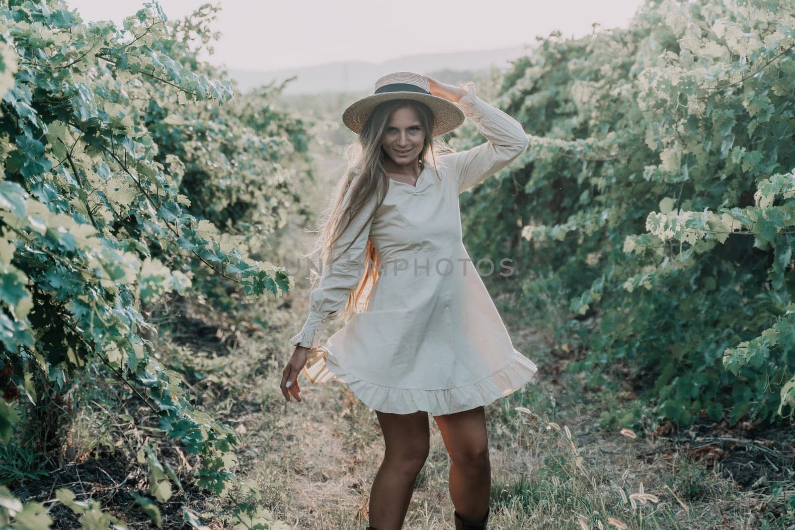 Woman at autumn winery. Portrait of happy woman holding glass of wine and enjoying in vineyard. Elegant young lady in hat toasting with wineglass smiling cheerfully enjoying her stay at vineyard. by panophotograph