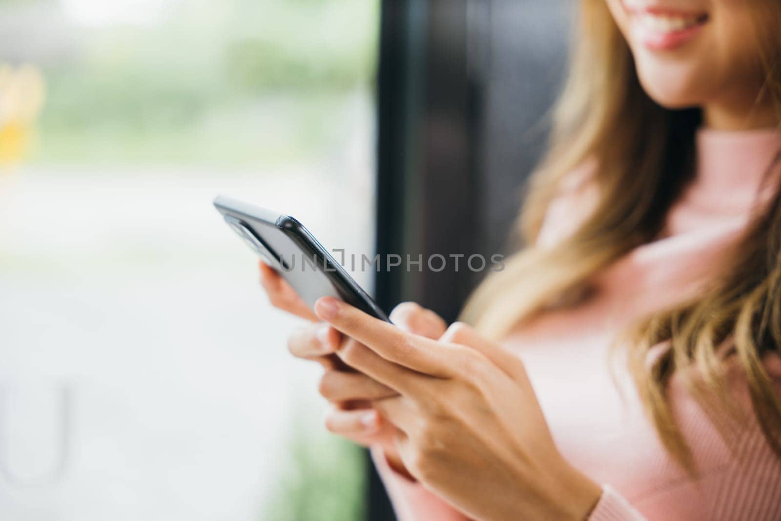 Young woman typing text message on smart phone device apps in cafe, beautiful female holding cellphone in hands and chatting social network with friends or reading email, mobile phone
