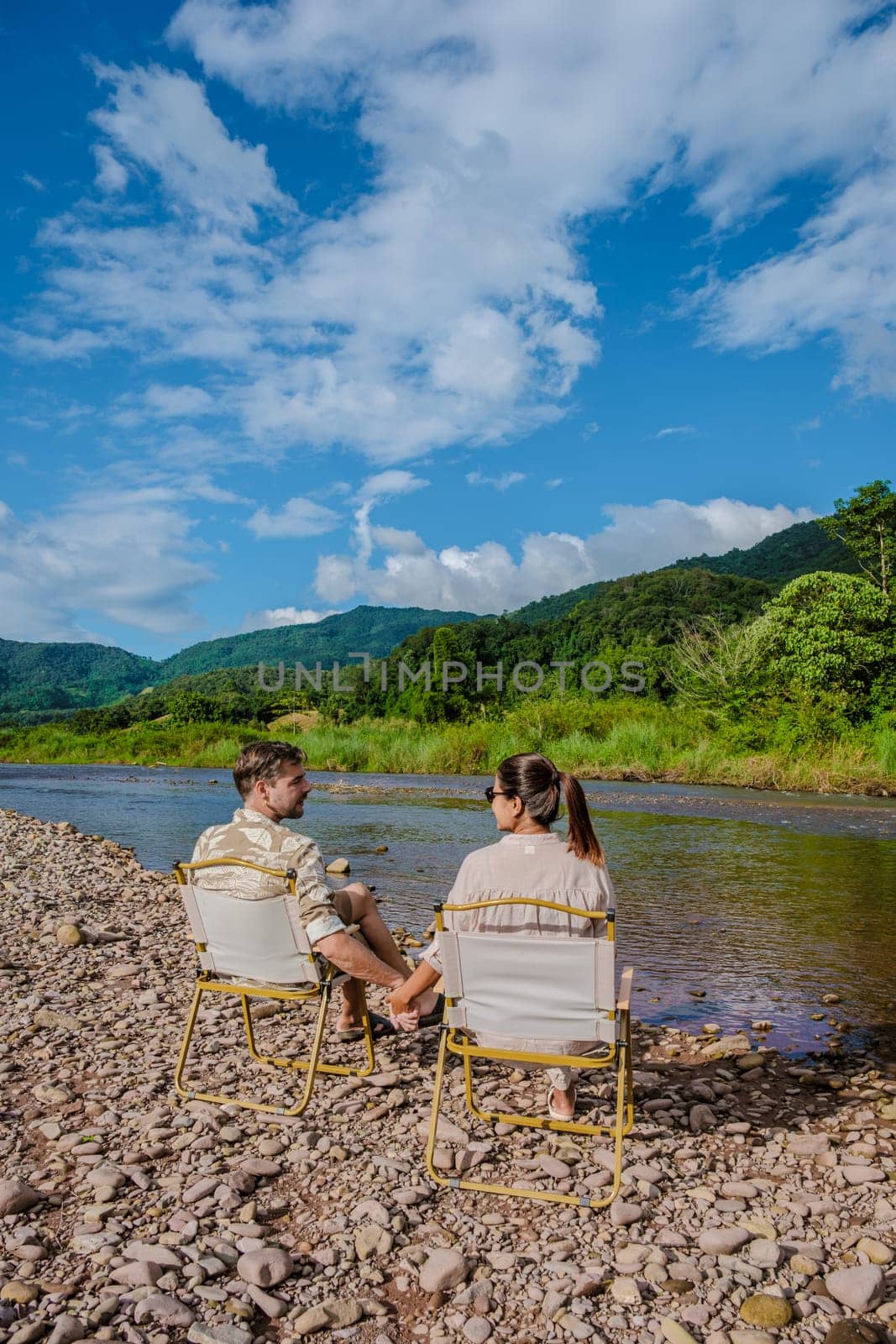a couple of men and woman camping at the river in Nan Sapan Thailand, men and woman relaxing in the mountains of Northern Thailand looking out over the river
