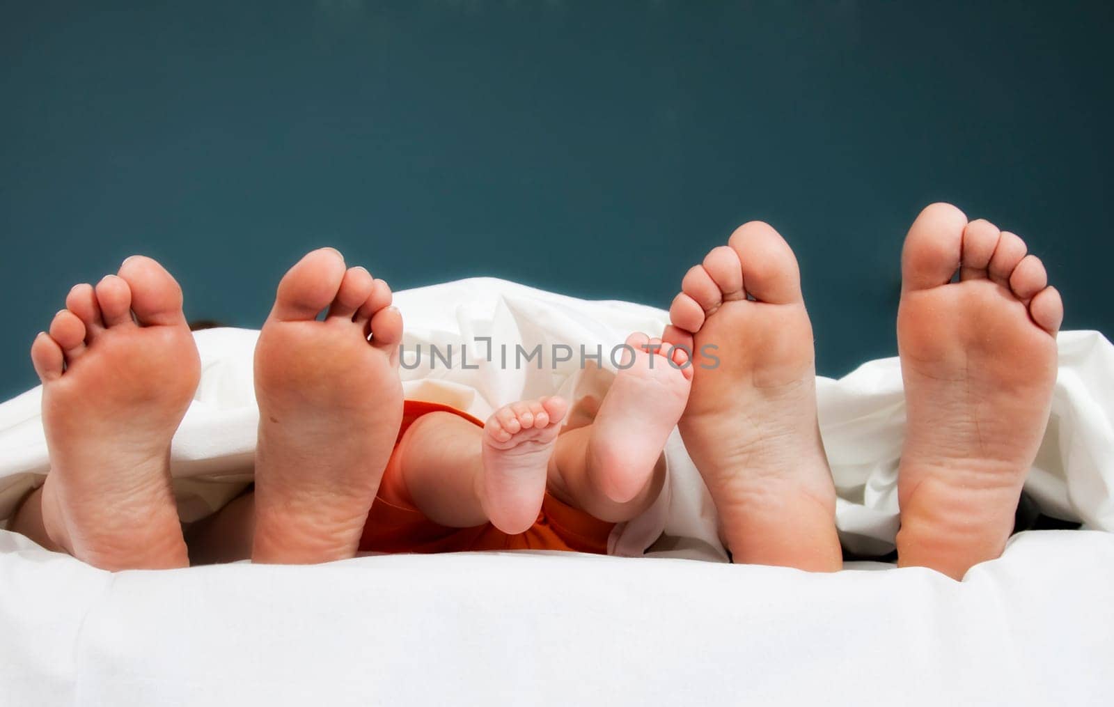 Tree pairs of legs of the happy family in bed - father, mother and baby