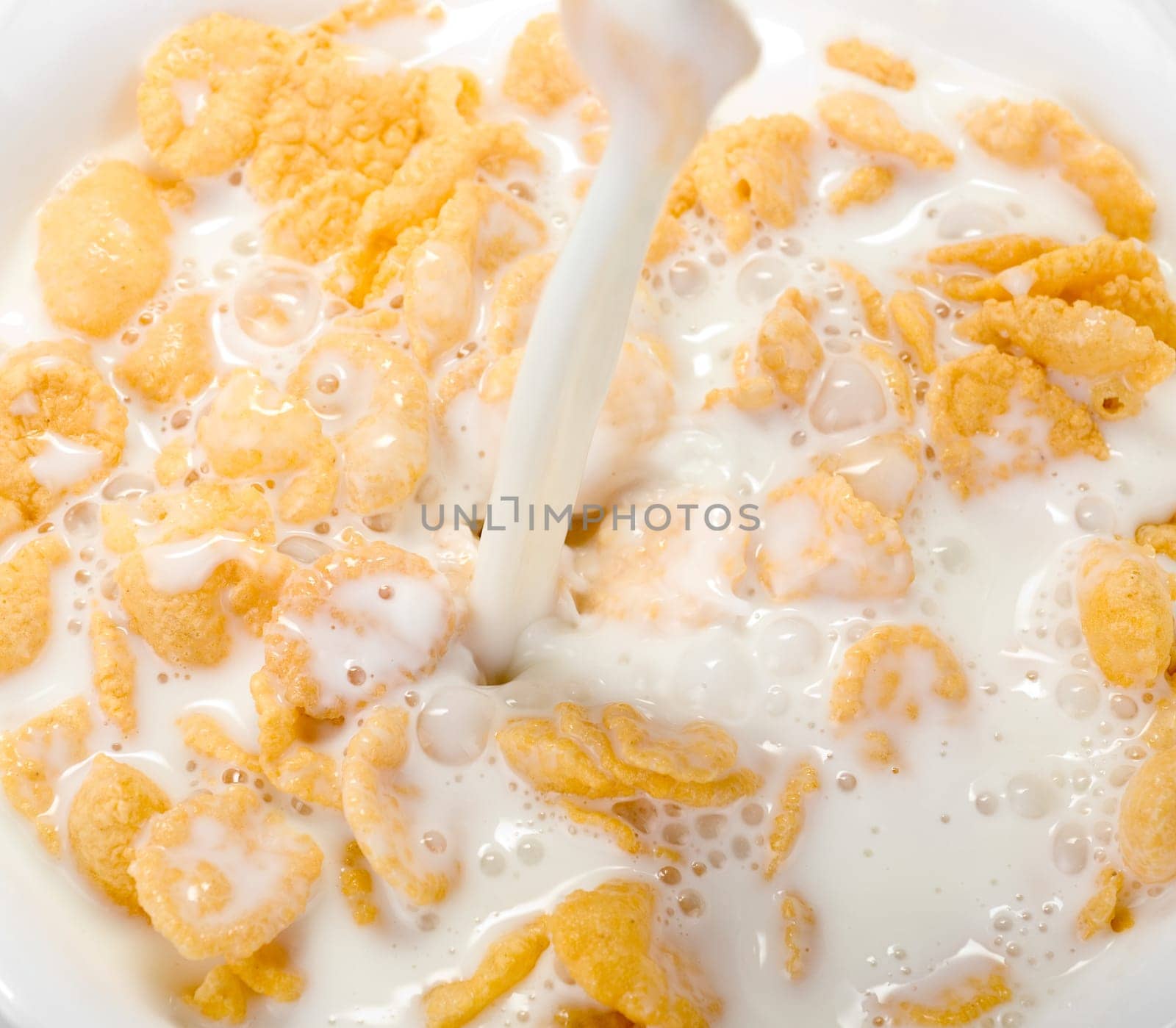 Milk pouring in a bowl of cornflakes closeup