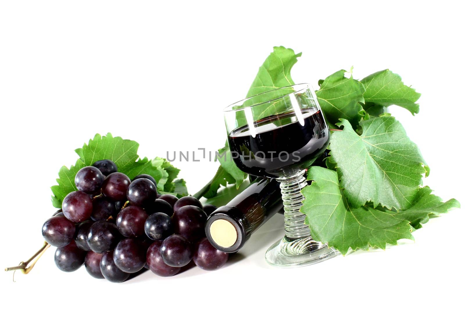 a bottle of red wine and fresh grapes against a white background