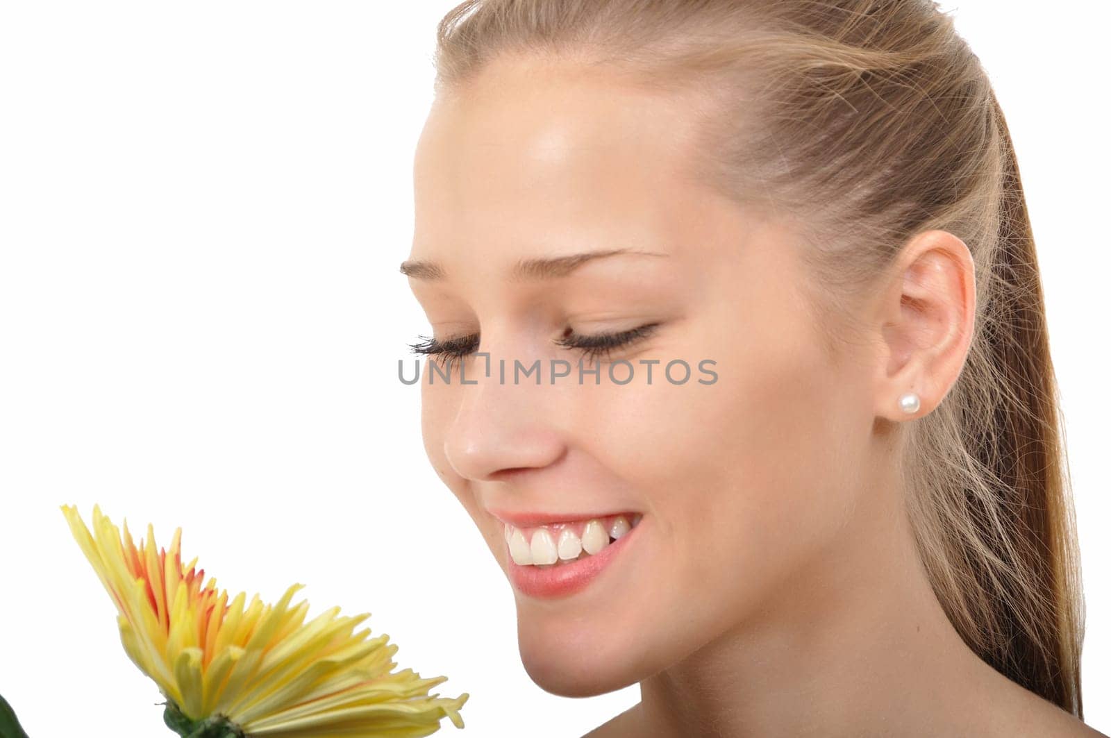 Attractive young woman smelling a yellow flower