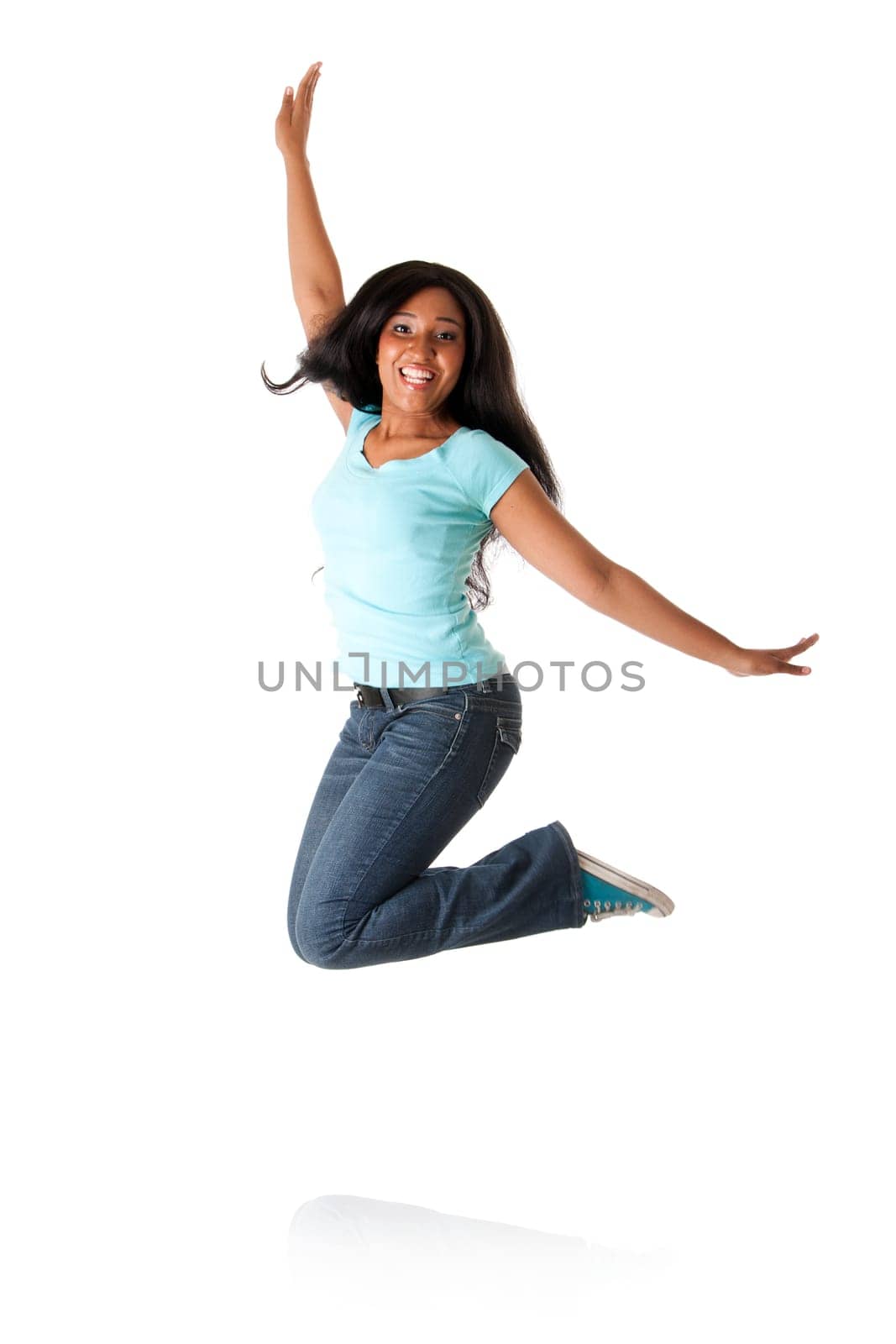 Beautiful happy smiling African Caribbean teenager jumping from happiness to celebrate, wearing blue shirt and jeans, isolated.