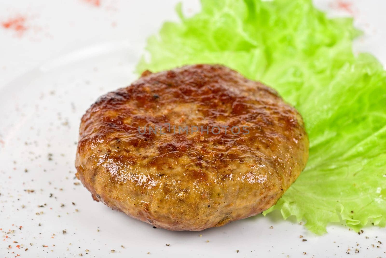 Beef cutlet closeup with lettuce on white plate