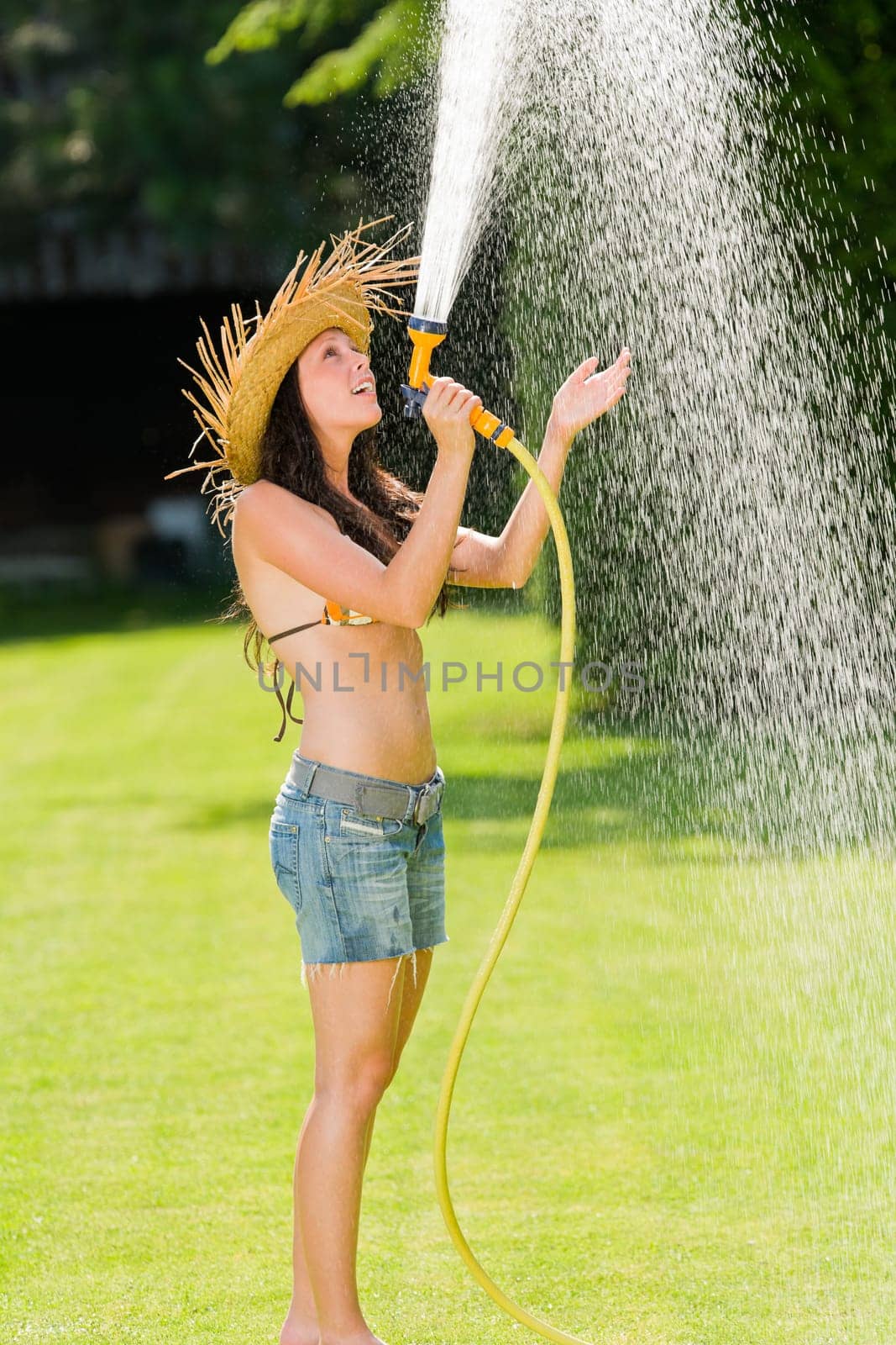Summer garden grass woman play with water hose sunny day