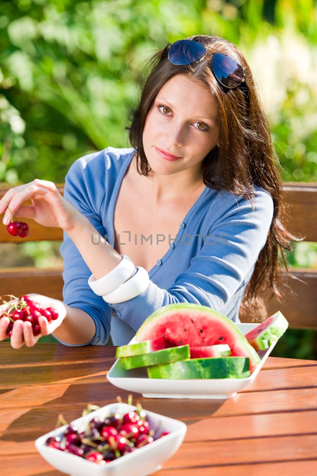 Beautiful young woman fresh summer melon cherries sitting garden terrace