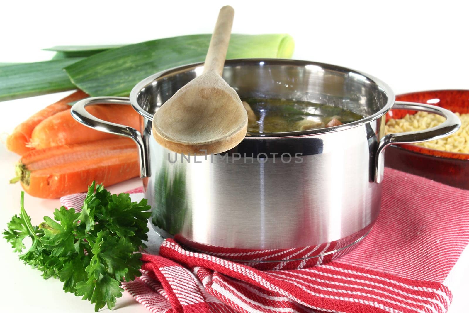 a pot of chicken soup with fresh vegetables