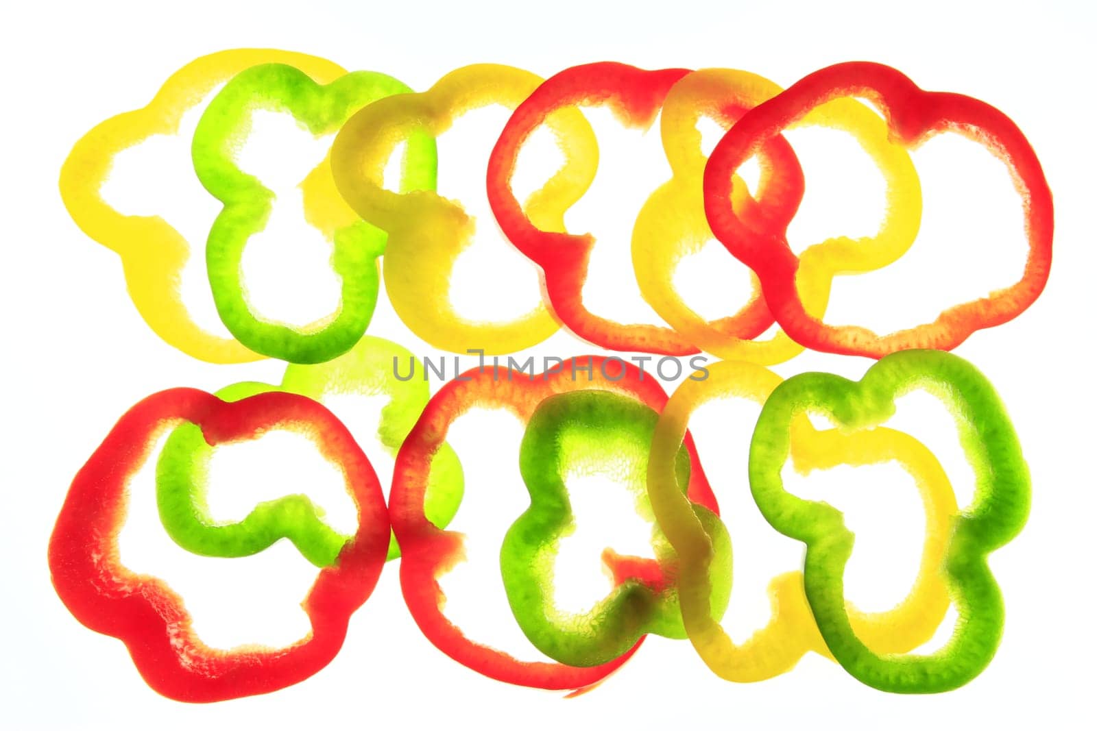 Slices of different colored sweet peppers isolated against white background