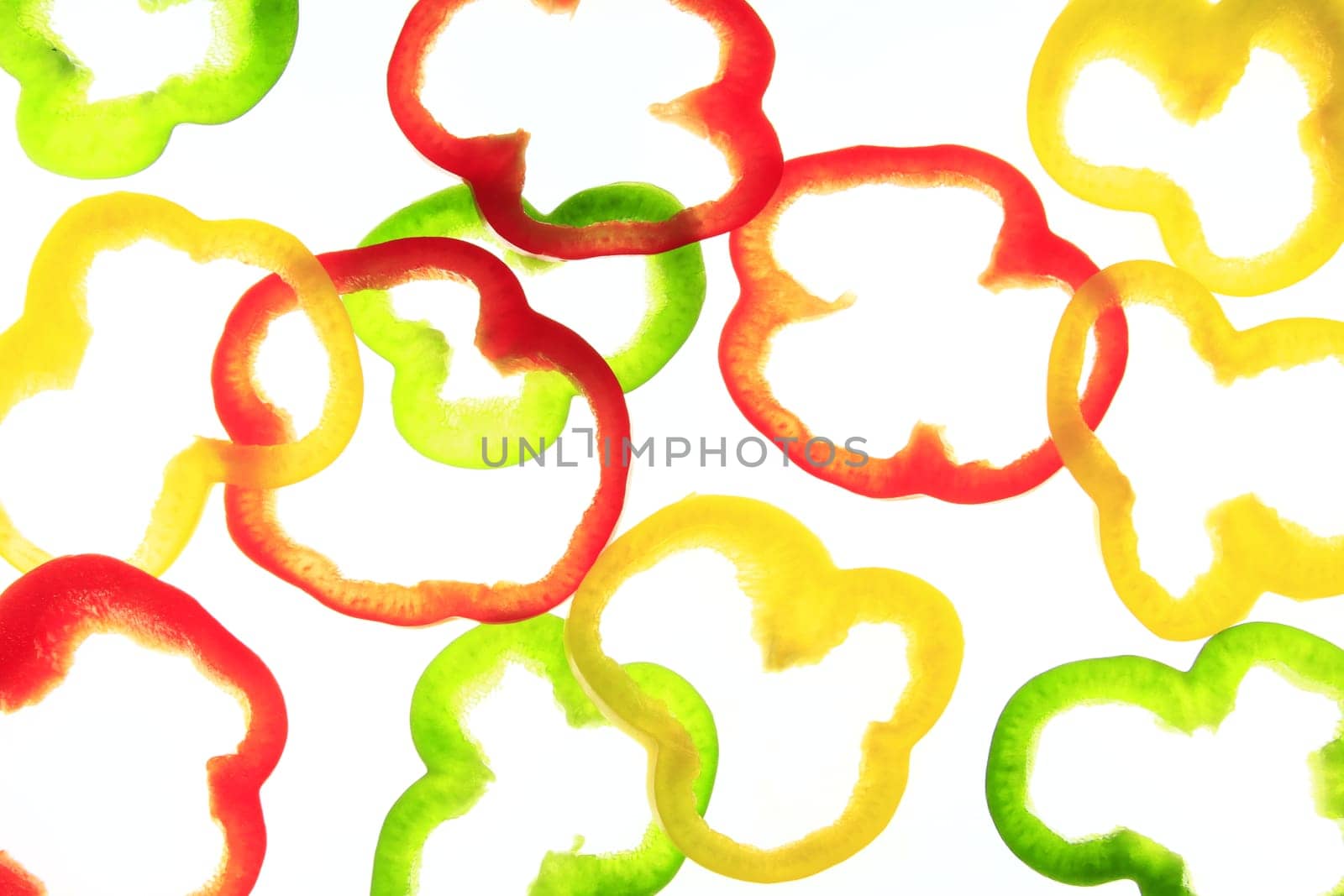Slices of different colored sweet peppers isolated against white background